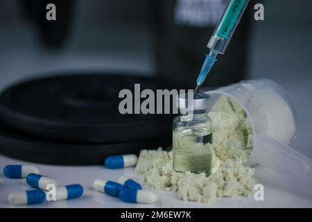 Pulver im Messlöffel mit Pillen und Spritze mit Nadel Stockfoto