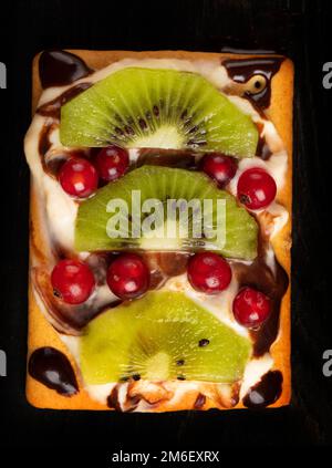 Wunderschöner süßer Dessertkuchen mit Sommerbeeren und Kiwi. Quadratischer Kuchen für einen Buffettisch. Stockfoto
