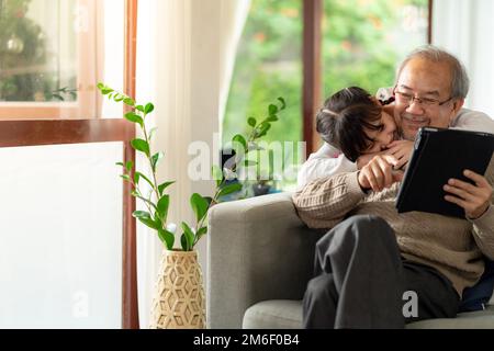 Älterer Mann mit Enkeltochter, der zusammen Tabletten einnimmt Stockfoto