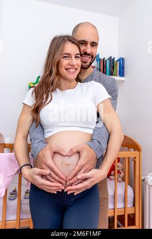 Ein glückliches, liebevolles Paar, das sich auf die Geburt vorbereitet. Schwangere Frau umarmte ihren großen Bauch und küsste von ihrem Partner. Stockfoto