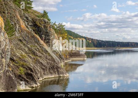 Schöner, breiter Herbstfluss zwischen Wäldern und felsiger Küste. Stockfoto