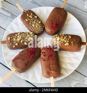 Eiscreme in einem gemütlichen Eis mit einem Holzstock liegt auf einem Teller. Stockfoto