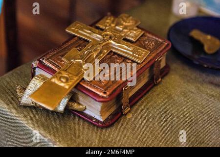 Alte bibel mit einem Schloss an der Bindung und einem Kreuz steht auf dem Buch. Stockfoto