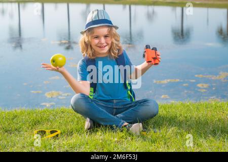 Reise- und Abenteuerkonzept. Kleiner Junge, Touristenforscher mit Fernglas auf der Natur. Entdeckung, Erkundung und Bildung. Stockfoto