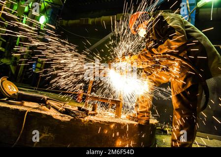 Schweißer kocht eine Stahlkonstruktion. Die Funken fliegen. Das Werk eines Schweißers. Stockfoto