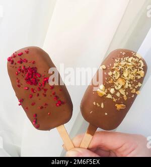 Zwei Eskimo-Eiscreme auf Holzstäbchen in der Hand. Stockfoto