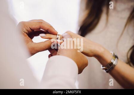 Der Bräutigam legt der Braut einen Ring an den Finger. Stockfoto