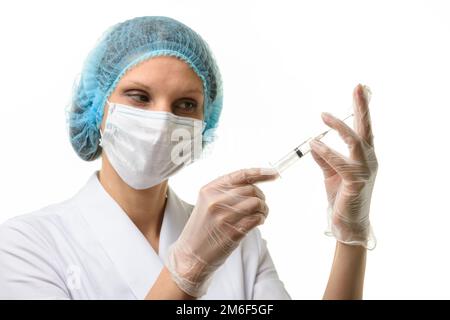 Krankenschwester in Maske und Handschuhe zieht Medizin mit einer Spritze Aus einer Ampulle Stockfoto