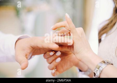 Die Braut steckt den Ring des Bräutigams an ihren Finger. Hochzeit Stockfoto