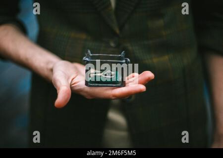 Ringe im Sarg. In den Händen einer Schachtel mit Ringen. Stockfoto