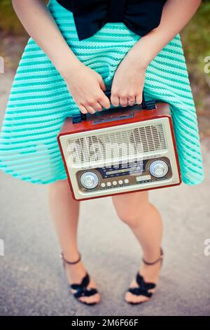 Ein Mädchen in einem Kleid mit einem Radio in der Hand. Retro-Style. Stockfoto