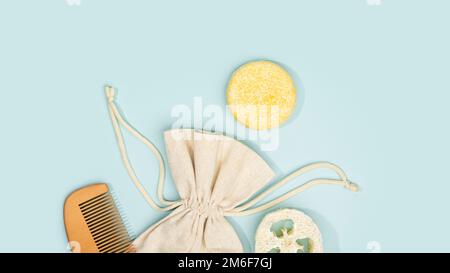 Nachhaltiger solider Shampoo-Riegel, Leinenbeutel, Holzkamm und natürlicher Luffa-Schwamm auf hellblauem Hintergrund. Umweltfreundliche Haarpflege. Plastikfrei Stockfoto