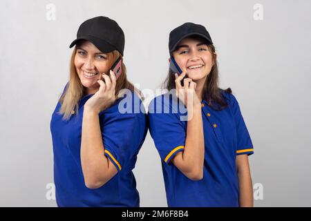 Mutter und Tochter stehen mit dem Rücken zueinander, reden am Telefon und schauen in den Rahmen Stockfoto