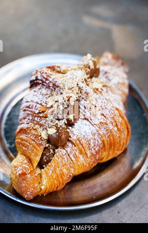 Französisches Croissant zum Frühstück in einem Café. Frische, köstliche, süße, gebackene Croissants mit Schokolade und Karamell am Morgen auf einem Café-Tisch. Ausgewählter Fokus. Hochwertiges Foto Stockfoto