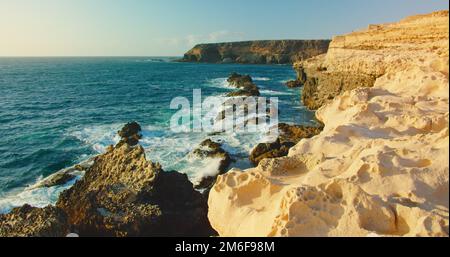 Die Wellen des Atlantischen Ozeans platzen auf vulkanischen Felshöhlen Kalkstein Sandsteinformationen. Klippen an der Küste der Kleinstadt Ajuy, Strand in Fuerteventura Stockfoto