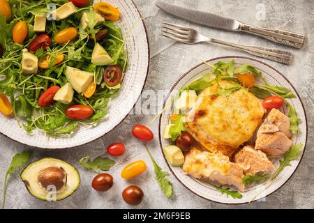 Mit Käse gebackener Lachs, serviert mit Gemüse. Stockfoto