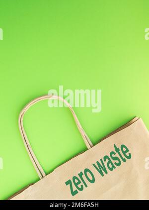 ECO Papierbeutel mit der Aufschrift „ZERO WASTE“ auf grünem Hintergrund, flache Position, Draufsicht Stockfoto