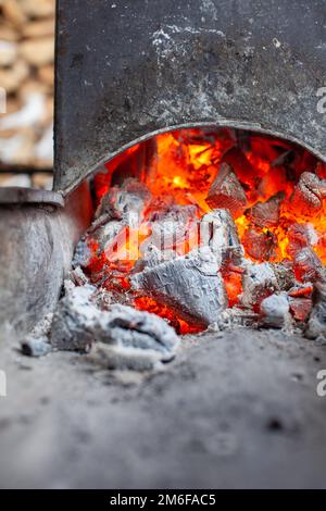 Kohlen in einem Metallgrill zum Braten von Fleisch und Gemüse verbrennen. Stockfoto