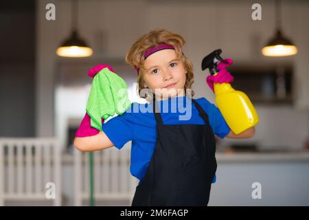 Ein Junge, der bei der Hausarbeit hilft, das Haus aufräumt. Konzept für die allgemeine Ordnung und Sauberkeit und Hausreinigung. Staubwedel und Handschuhe für die Reinigung. Küche zu Hause Stockfoto