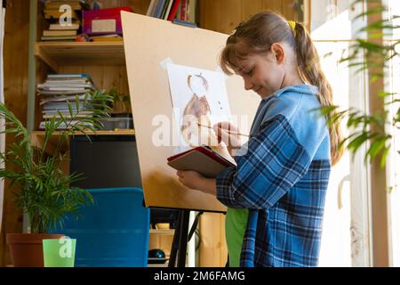 Ein zehnjähriges Mädchen schaut sich ein Video-Tutorial an und zeichnet ein Bild auf einem Tablet Stockfoto