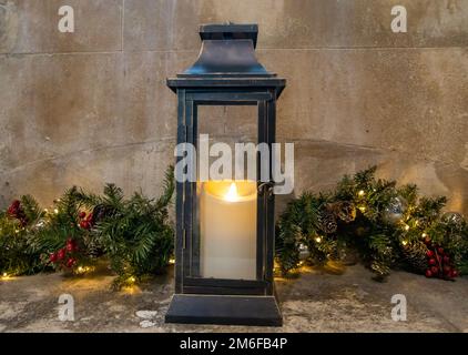 Eine alte Sturmlaterne und Kerze vor der Weihnachtsdekoration in Winchester, Hampshire, Großbritannien Stockfoto