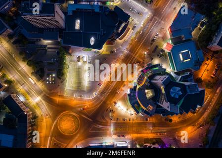 Luftdrohnenansicht der Nacht beleuchtete Innenstadt-Verkehrszirkel in der Nähe des Atrium-Gebäudes, Langzeitbelichtung Stockfoto