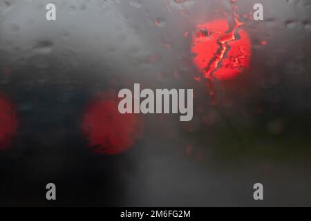Zwei unscharfe rote Lichter im Hintergrund bei Regen Stockfoto