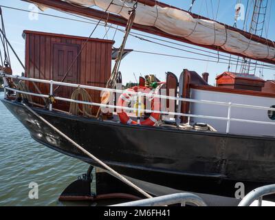 Der Bug eines Segelschiffs mit einer kleinen Holzkabine und einem roten Rettungsring Stockfoto