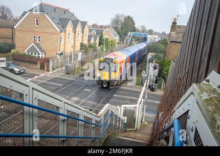 London - Dezember 2022: South Western Railway, der einen Bahnübergang im Gebiet Richmond im Südwesten Londons überquert Stockfoto