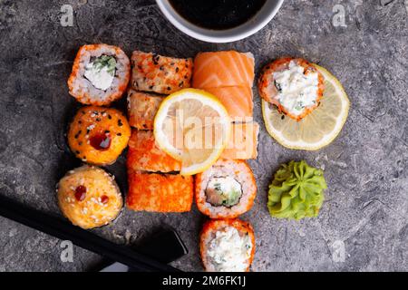 Sushi-Brötchen, serviert am grauen Tisch. Flach verlegt. Schließen Stockfoto
