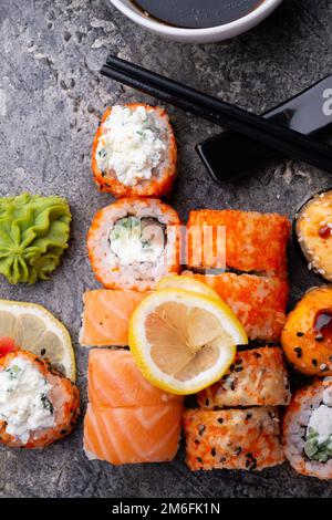 Sushi-Brötchen, serviert am grauen Tisch. Flach verlegt. Schließen Stockfoto