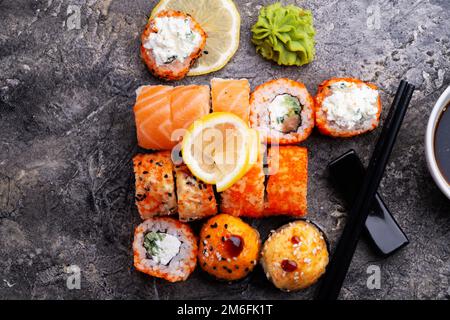 Sushi-Brötchen, serviert am grauen Tisch. Flach verlegt. Schließen Stockfoto