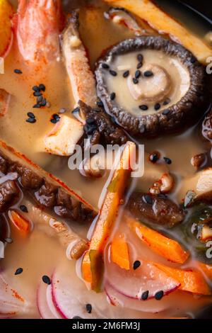 Miso Suppe mit Muscheln, Garnelen, Shiitake-Pilzen und Gemüse. Makroaufnahme. Flach verlegt Stockfoto