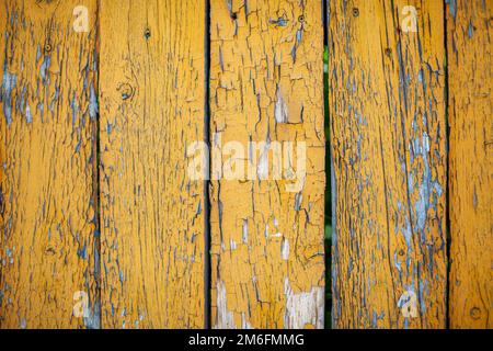 Holzstruktur mit gelber Flockfarbe. Abblätternde Farbe auf verwittertem Holz Stockfoto