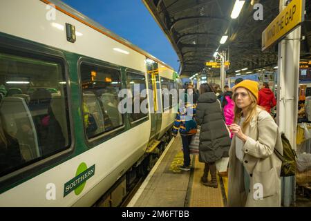 London - Dezember 2022: Passagiere auf dem Bahnsteig Clapham Junction steigen in einen Southern Train ein Stockfoto