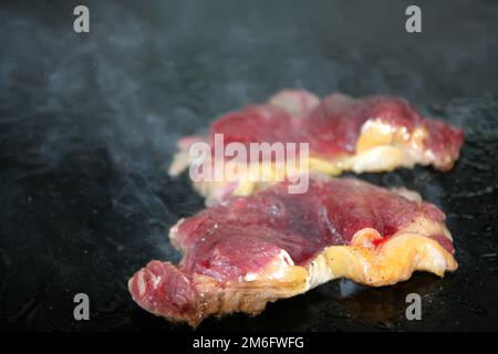 Geschnittenes Steak mit fettem Grillgut und weißem Rauch Stockfoto