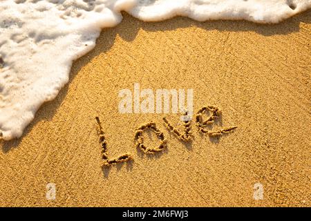 Das Wort LIEBE im Sand am Strand geschrieben Stockfoto