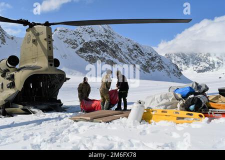 Auf dem Kahiltna-Gletscher parkt ein CH-47F-Chinook-Hubschrauber, während die Soldaten der Bravo Company, des 1. Bataillons, des 52. Luftfahrtregiments, auch bekannt als Sugar Bears, die Ausrüstung für den National Park Service im Bergsteigerbasislager entladen. (FOTO DER US-Armee, Eve Baker, Fort Wainwright Public Affairs Office) Stockfoto