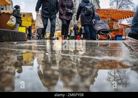 04. Januar 2023, Hessen, Frankfurt/Main: Passanten und Kunden auf dem Wochenmarkt im Stadtteil Bornheim gehen nach einem der zahlreichen Regenschauer über den nassen Bürgersteig. Foto: Frank Rumpenhorst/dpa Stockfoto