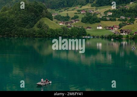 Schweizer Dorf Lungern mit seinen traditionellen Häusern und dem alten Kirchturm Alter Kirchturm entlang des wunderschönen smaragdgrünen Sees Lungerers Stockfoto