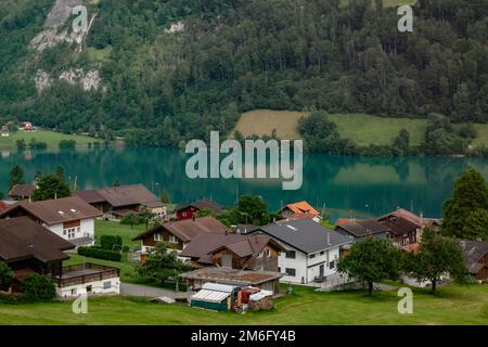 Schweizer Dorf Lungern mit seinen traditionellen Häusern und dem alten Kirchturm Alter Kirchturm entlang des wunderschönen smaragdgrünen Sees Lungerers Stockfoto