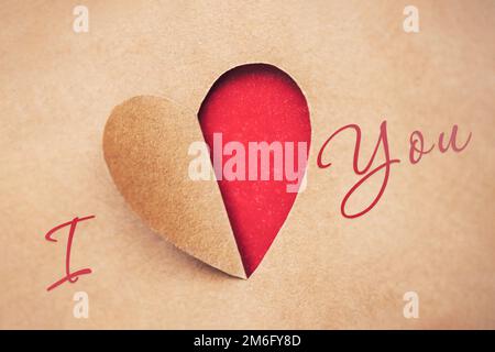 Valentinstag-Grußkarte mit einem aus Papier geschnittenen Herzen und Inschrift Ich liebe dich. Stockfoto