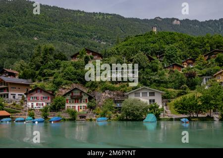 Brienzersee, Brienzersee mit türkisfarbenem Wasser - traditionelle Holzhäuser in der Nähe von Interlaken mit Schweizer Alpen im Hintergrund, Stockfoto