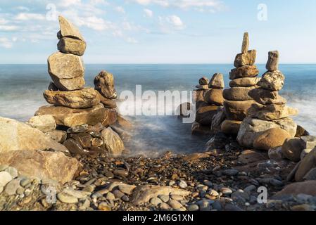 Pyramiden von Meeressteinen an der Küste.Eingang zum Meer. Stockfoto