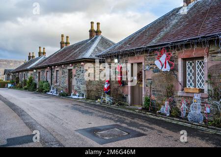 Weihnachtsdekorationen vor den Häusern entlang der Pier Road im malerischen Dorf Luss am Loch Lomond in Schottland, Großbritannien Stockfoto