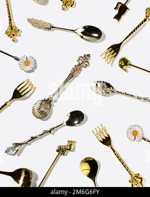 Muster aus goldenen Dessertlöffeln und Gabeln auf weißem Hintergrund, Draufsicht Stockfoto