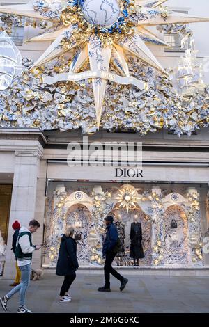 Lebhafte Szene vor dem Dior Store in der New Bond Street, die am 2. Dezember 2022 in London, Großbritannien, mit ihren Weihnachtsdekorationen glitzert. Die Bond Street ist eine der Hauptstraßen im West End-Einkaufsviertel und ist sehr vornehm. Es ist seit dem 18. Jahrhundert eine modische Einkaufsstraße. Die Reichen und Reichen kaufen hier hauptsächlich hochwertige Mode und Schmuck. Stockfoto