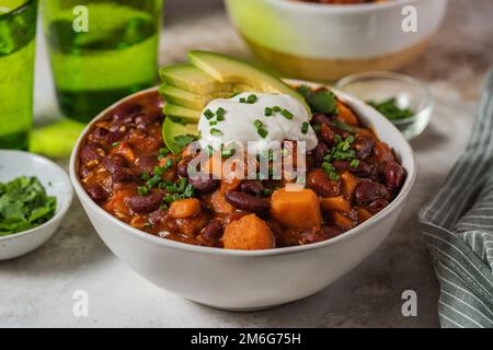 Chili Süßkartoffeln und schwarze Bohnen mit Tomaten, Sellerie in einer Pfanne auf dem Tisch. Horizontale Draufsicht von oben Stockfoto