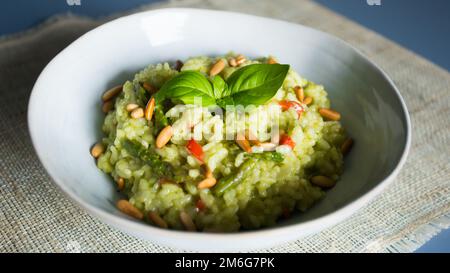 Risotto mit grünem Pesto. Risotto ist ein norditalienisches Reisgericht, das mit Brühe zubereitet wird, bis es eine cremige Konsistenz erreicht. Stockfoto