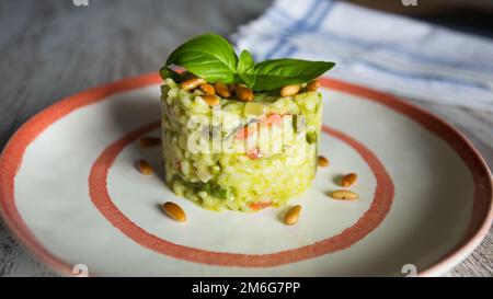 Risotto mit grünem Pesto. Risotto ist ein norditalienisches Reisgericht, das mit Brühe zubereitet wird, bis es eine cremige Konsistenz erreicht. Stockfoto